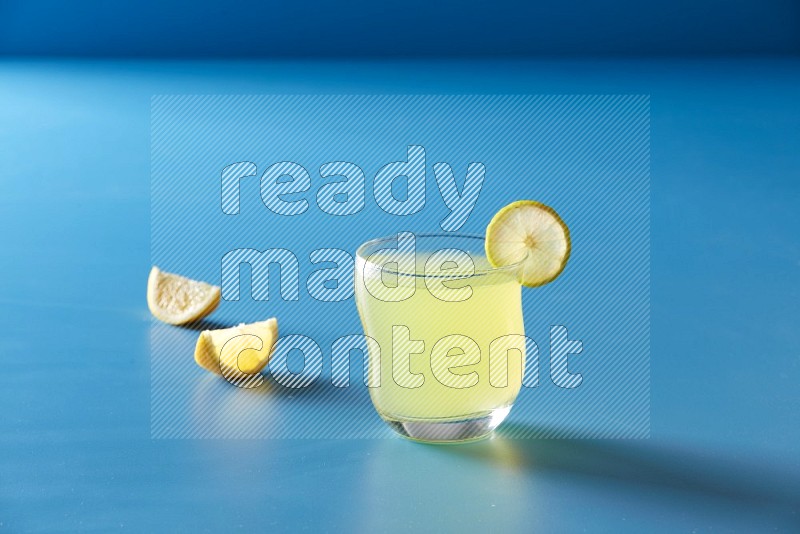 glass of lemon juice with lemon slice  on blue background