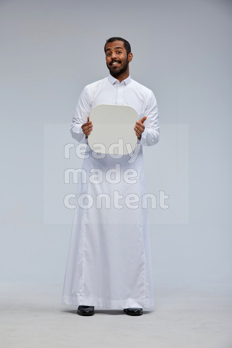 Saudi man wearing Thob standing holding social media sign on Gray background