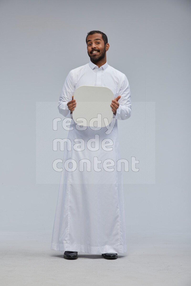 Saudi man wearing Thob standing holding social media sign on Gray background