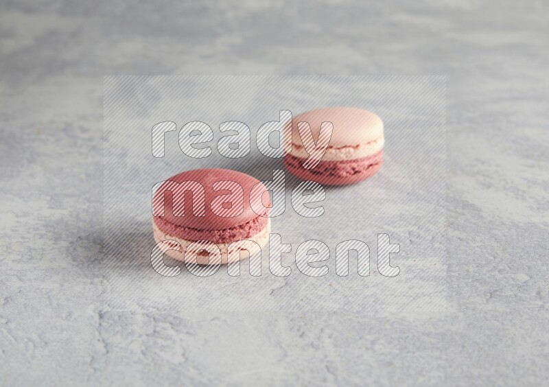 45º Shot of two Pink Litchi Raspberry macarons  on white  marble background