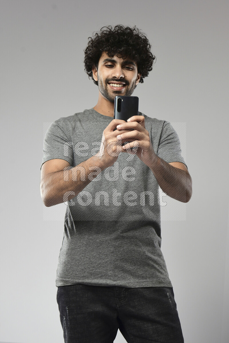 A man wearing casual standing and shooting with his phone on white background