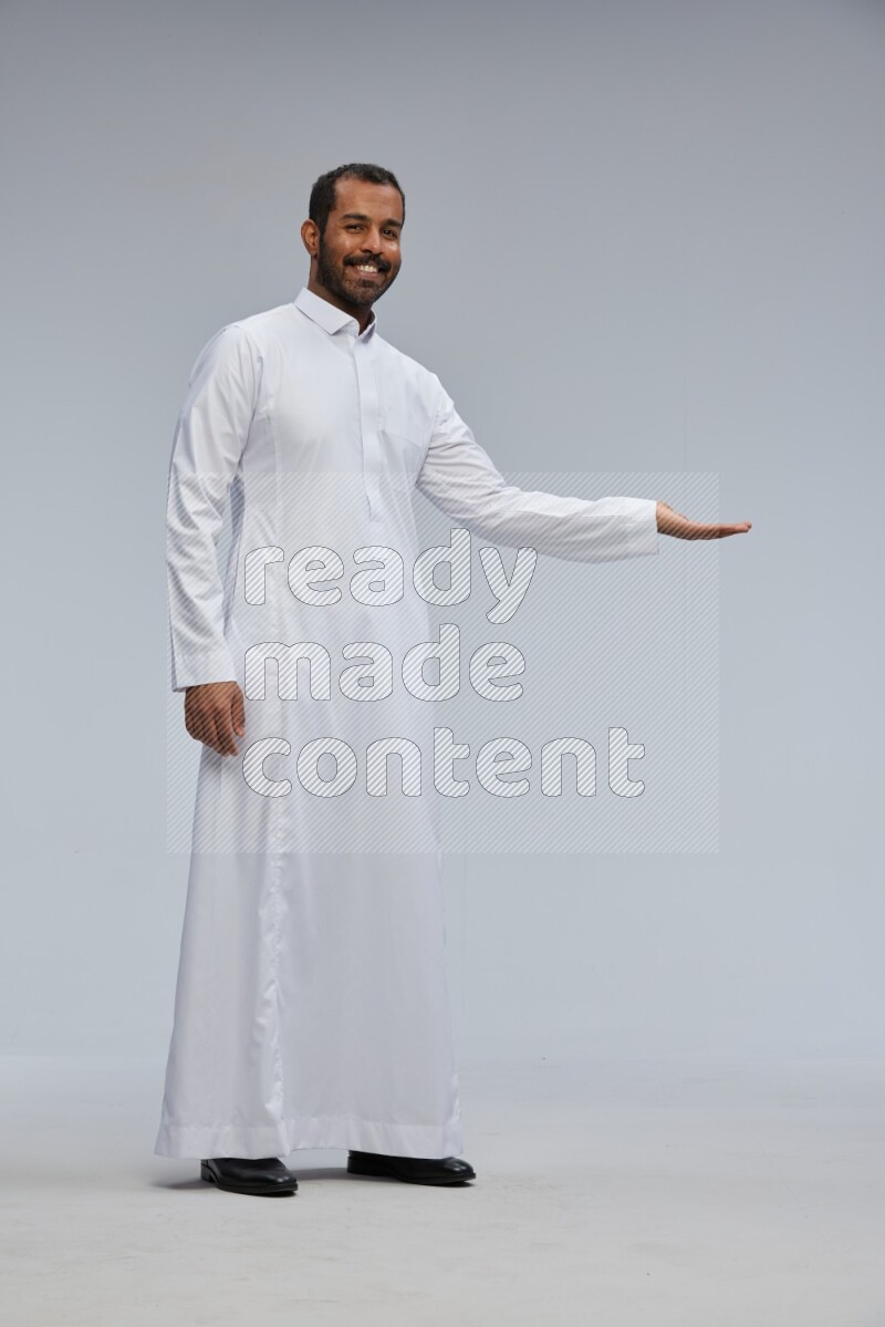 Saudi man Wearing Thob standing interacting with the camera on Gray background