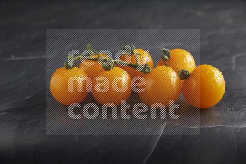 Yellow cherry tomato vein on a textured black slate background 45 degree