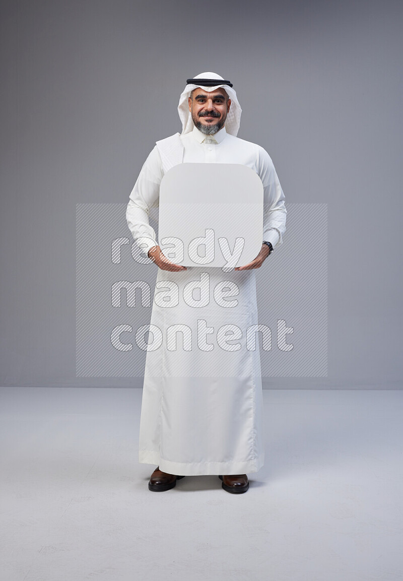 Saudi man Wearing Thob and white Shomag standing holding social media sign on Gray background