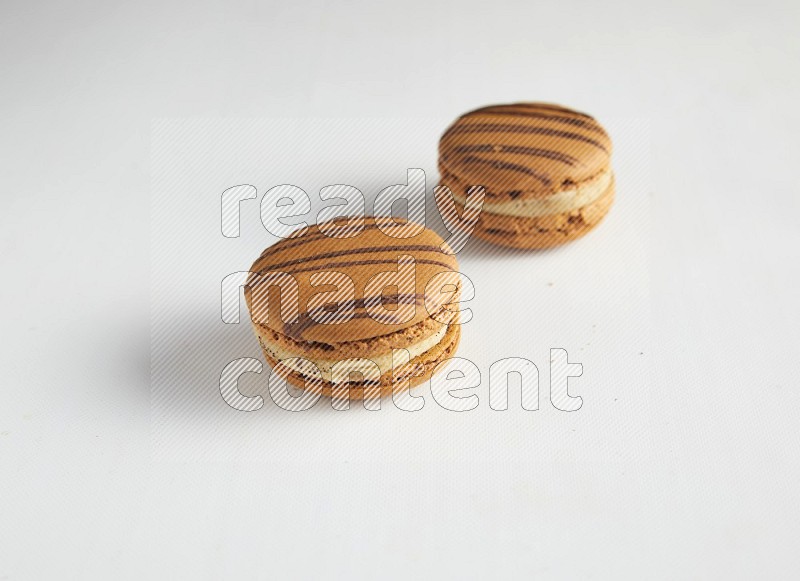 45º Shot of two light brown  Almond Cream macarons on white background
