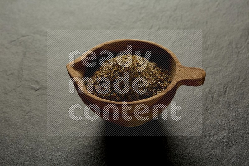 wooden round sauce bowl filled with herbs on grey textured countertop