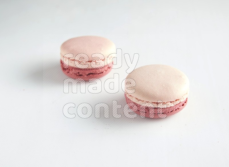 45º Shot of two Pink Litchi Raspberry macarons on white background