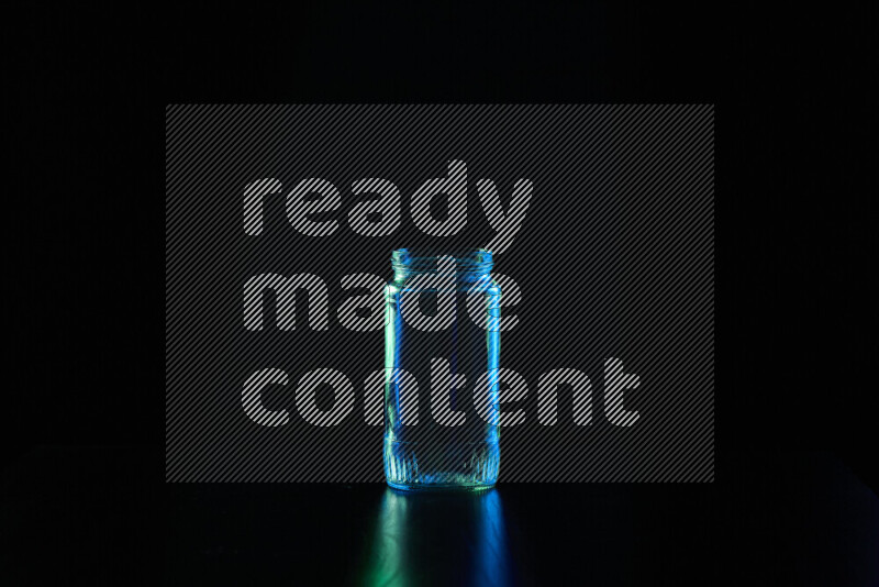 Glassware with rim light in blue and green against black background