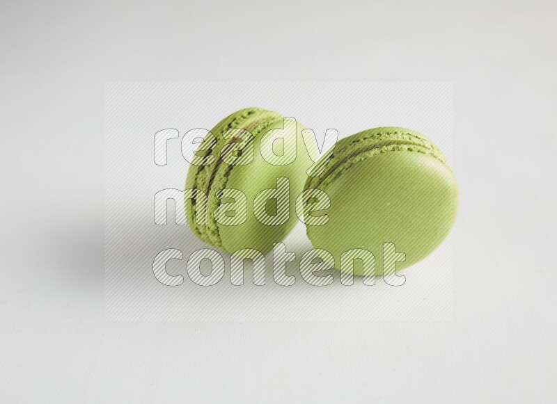 45º Shot of two Green Pistachio macarons on white background