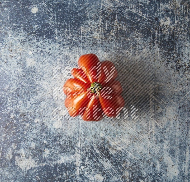 Single Topview Heirloom Tomato on a textured rustic blue background
