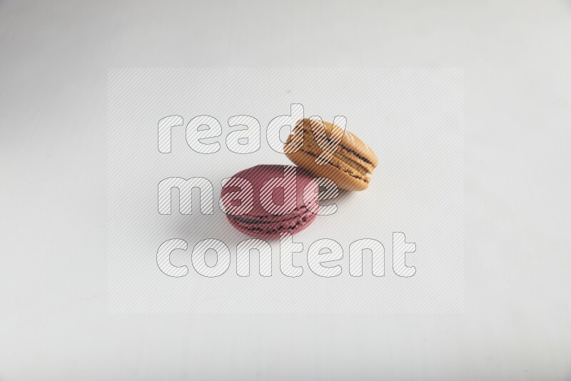 45º Shot of of two assorted Brown Irish Cream, and Red Cherry macarons on white background