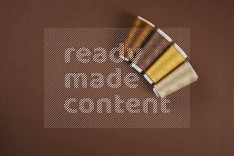 A yellow collection of sewing and tailoring tools arranged on a brown background