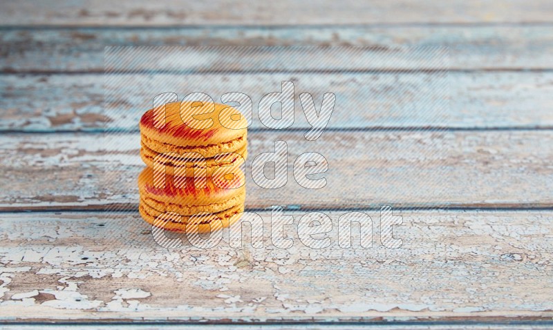 45º Shot of two orange Exotic macarons on light blue wooden background