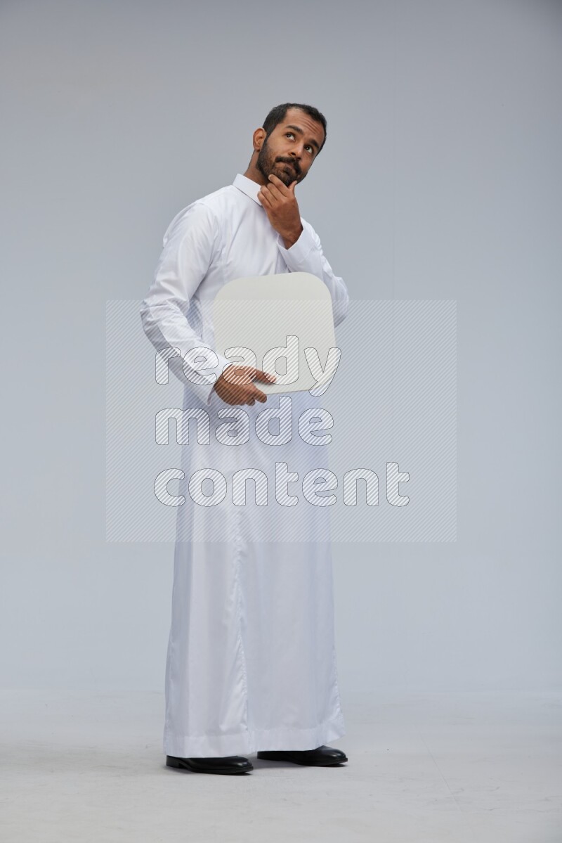 Saudi man wearing Thob standing holding social media sign on Gray background