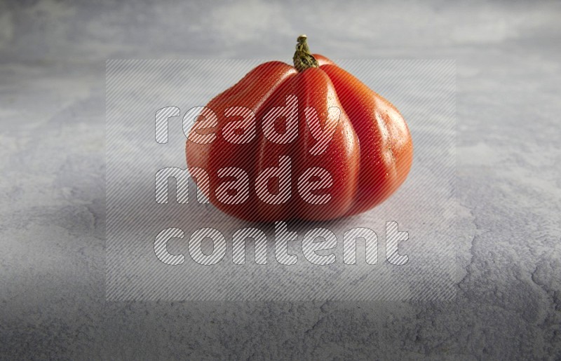 45 degree single heirloom tomato on a light blue textured background