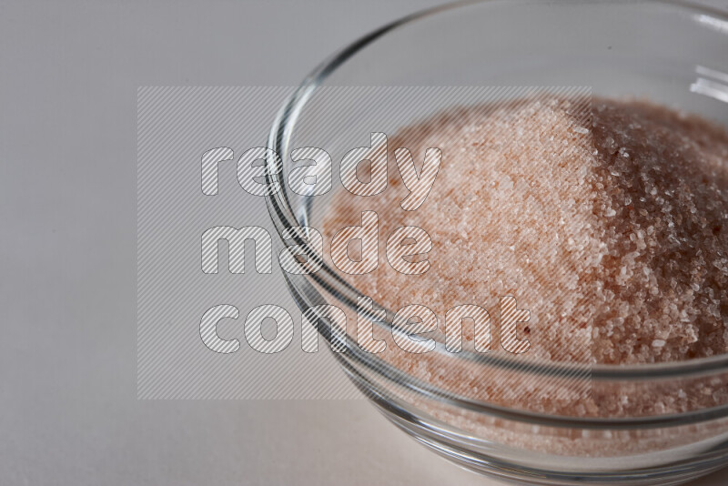 A glass bowl full of fine himalayan salt on white background