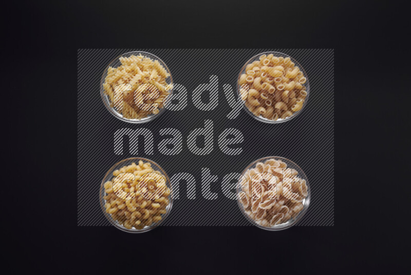 أنواع مختلفة من المعكرونة في وعاء زجاجي علي خلفية سوداء