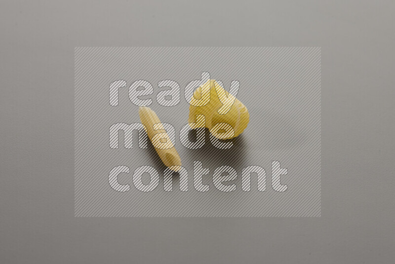 Mini penne pasta with other types of pasta on grey background