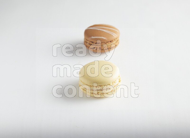 45º Shot of of two assorted Brown Irish Cream, and Yellow Vanilla macarons on white background