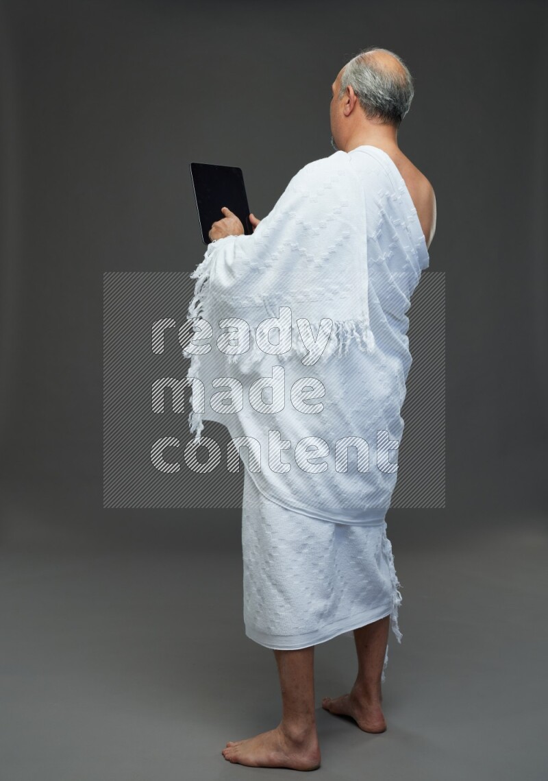 A man wearing Ehram Standing working on tablet on gray background