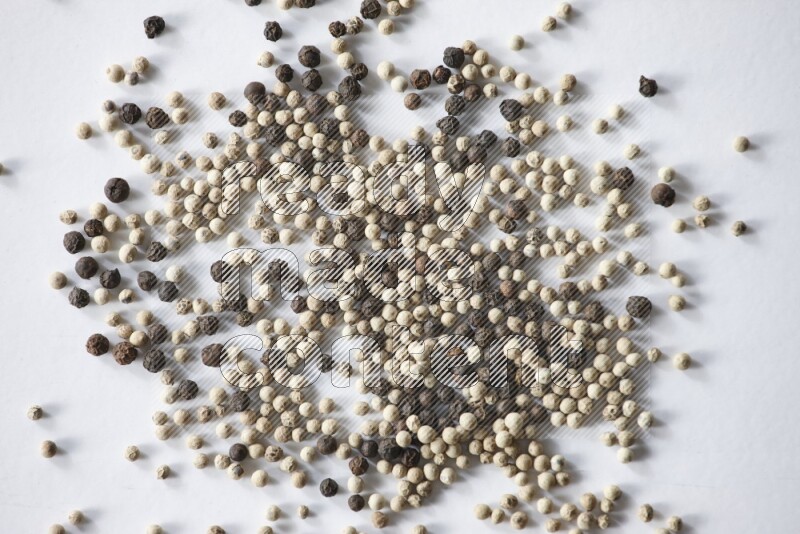 حبوب الفلفل المختلطة السوداء والبيضاء على أرضية بيضاء