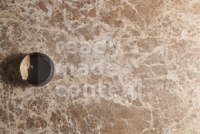 A multicolored pottery bowl on beige marble background