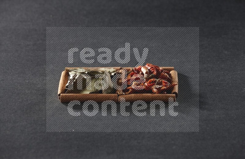 2 squares of cinnamon sticks full of chilis and bay laurel leaves on black flooring