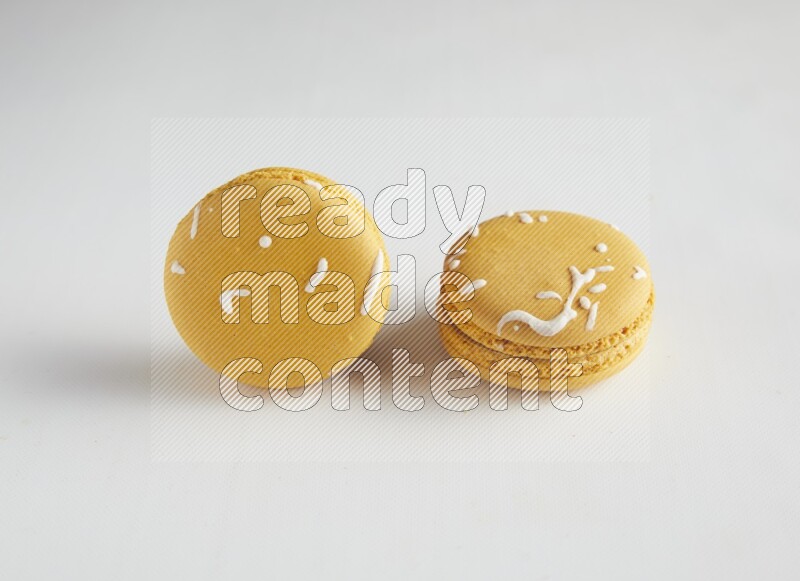 45º Shot of two Yellow Piña Colada macarons on white background