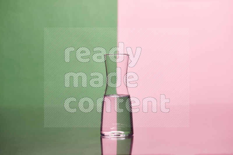 The image features a clear glassware filled with water, set against green and rose background