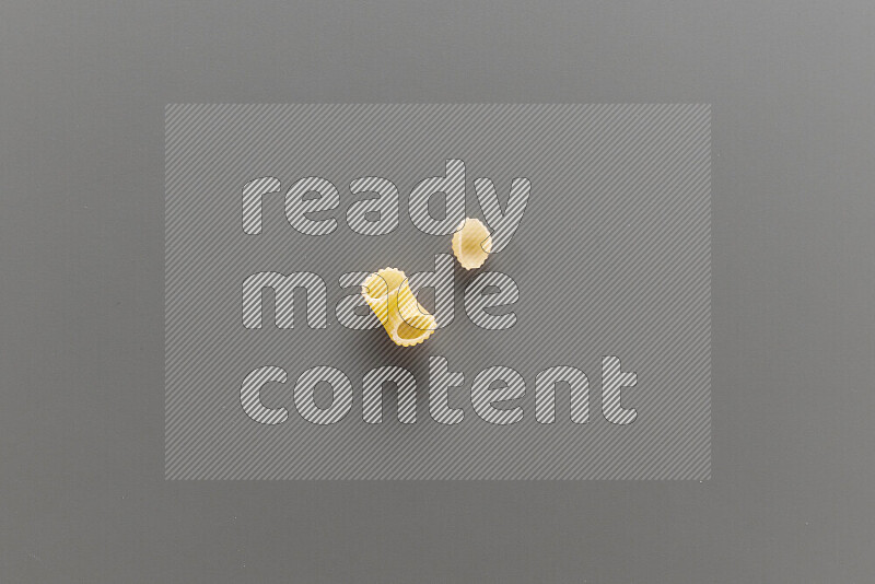 Elbow pasta with other types of pasta on grey background