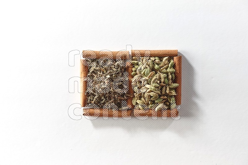 2 squares of cinnamon sticks full of cardamom and dried basil on white flooring