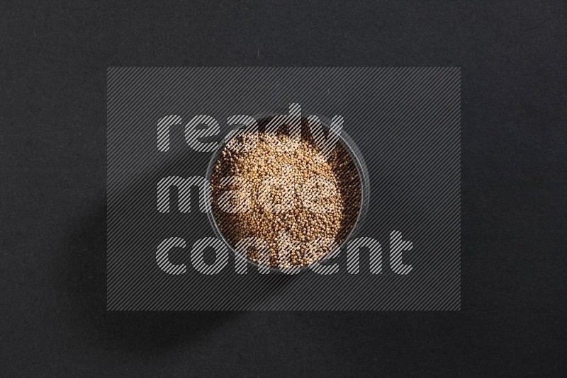 A black pottery bowl full of mustard seeds on black flooring in different angles