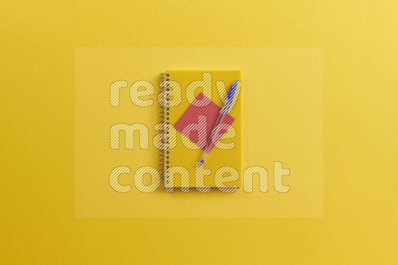 A yellow notebook with different school supplies on yellow background