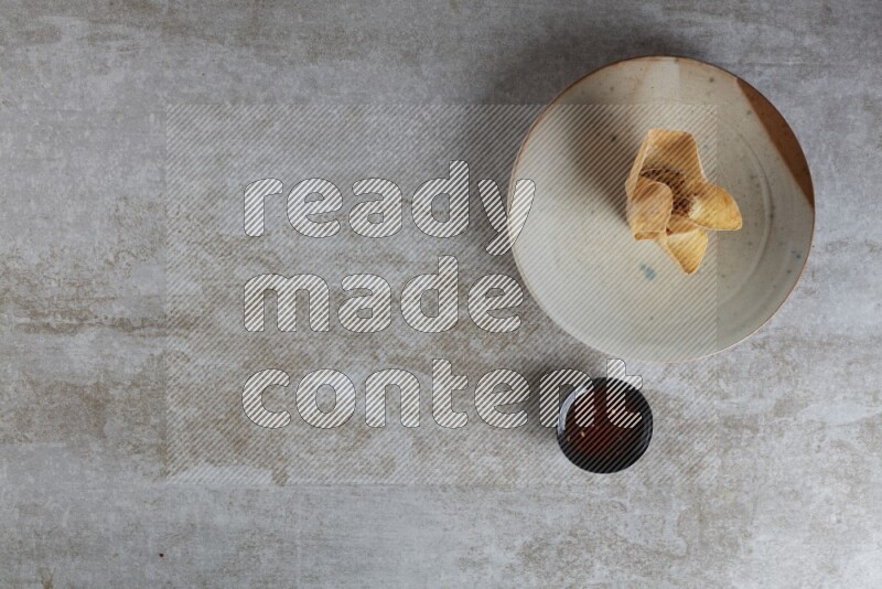 wonton cups with soy sauce ramkin on multi colored pottery on grey textured counter top