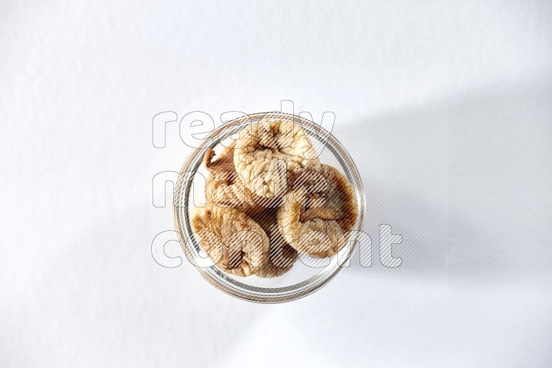 A glass bowl full of dried figs on a white background in different angles