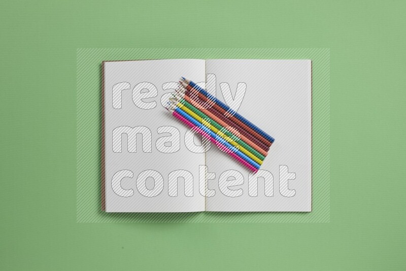 دفتر ملاحظات مفتوح فارغ مع مستلزمات مدرسية مختلفة على خلفية خضراء