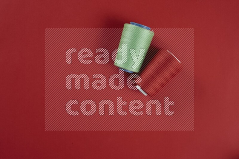 A green and red collection of sewing and tailoring tools arranged on a red background