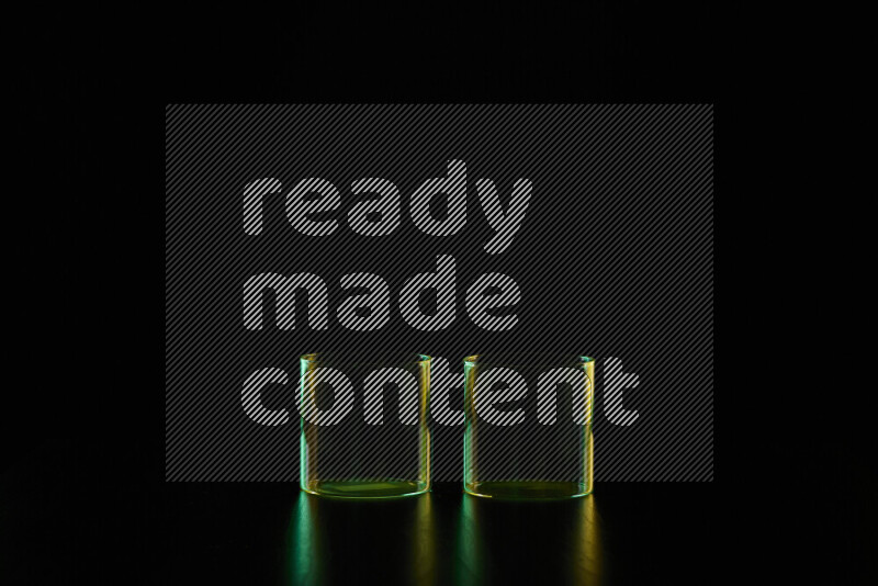 Glassware with rim light in green and yellow against black background