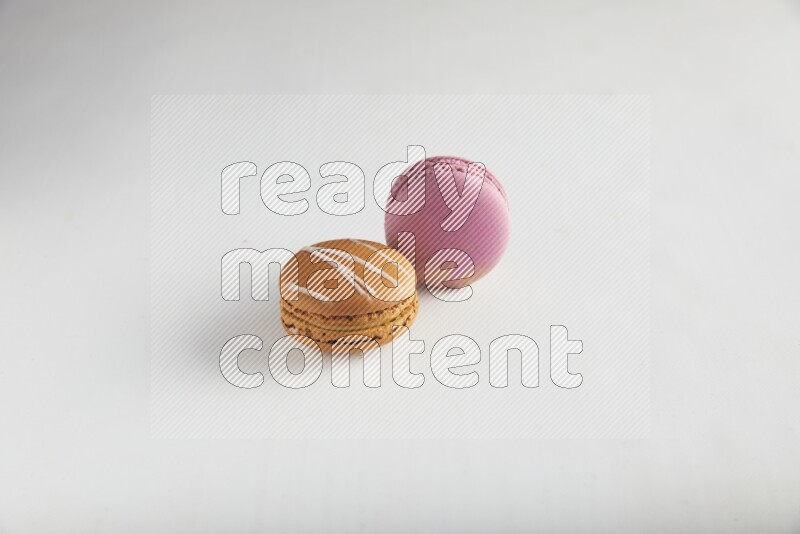 45º Shot of of two assorted Brown Irish Cream, and Purple Strawberry macarons on white background