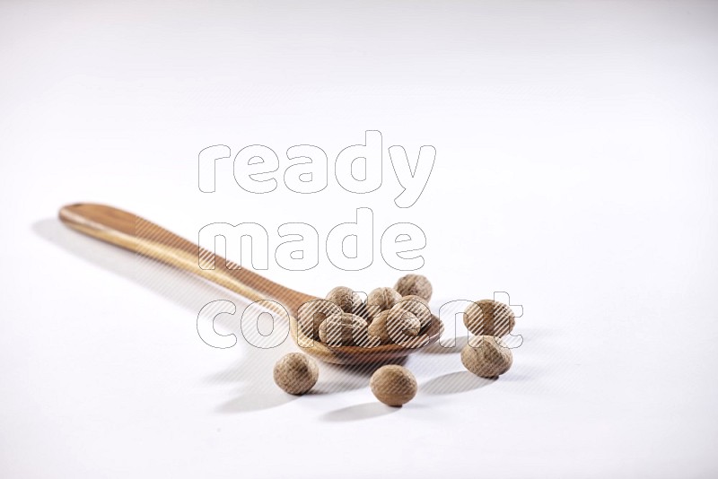 A wooden ladle full of nutmeg on a white flooring in different angles