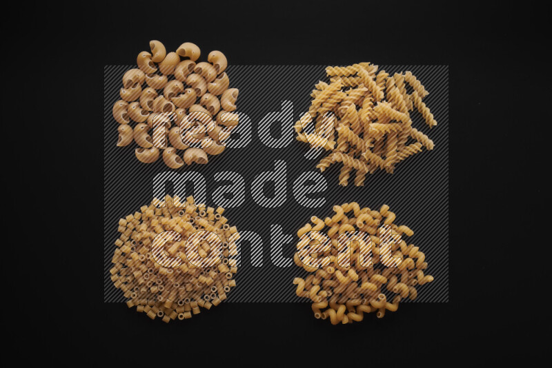 Different pasta types in bunches on black background