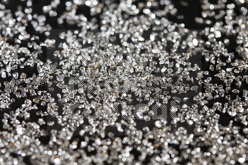 Silver shimmering fragments of glass scattered on a black background