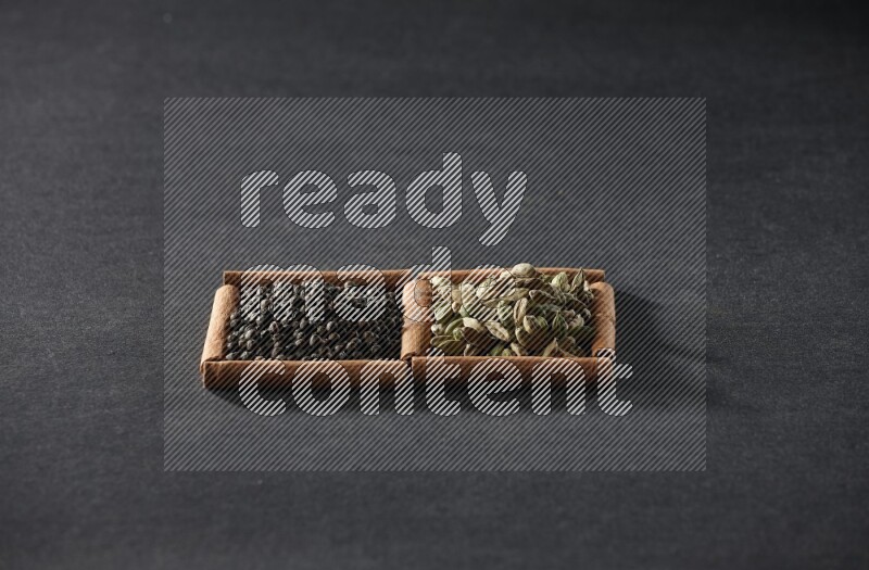 2 squares of cinnamon sticks full of black peppers and cardamom on black flooring