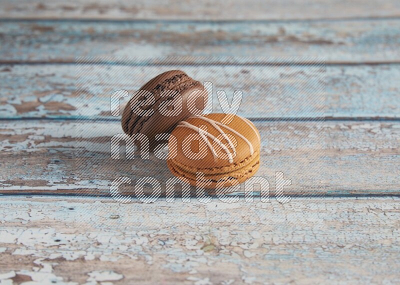 45º Shot of of two assorted Brown Irish Cream, and Brown Dark Chocolate macarons on light blue background