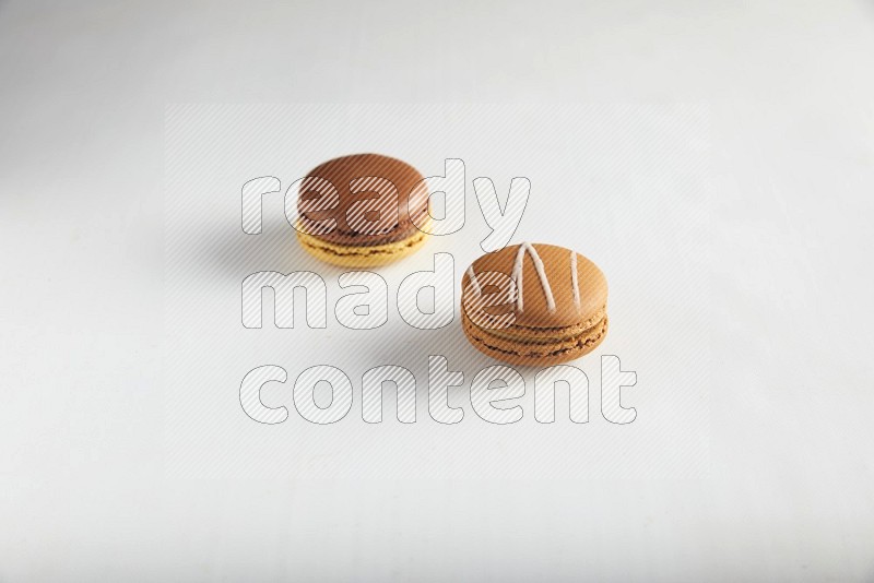 45º Shot of of two assorted Brown Irish Cream, and Yellow, and Brown Chai Latte macarons on white background