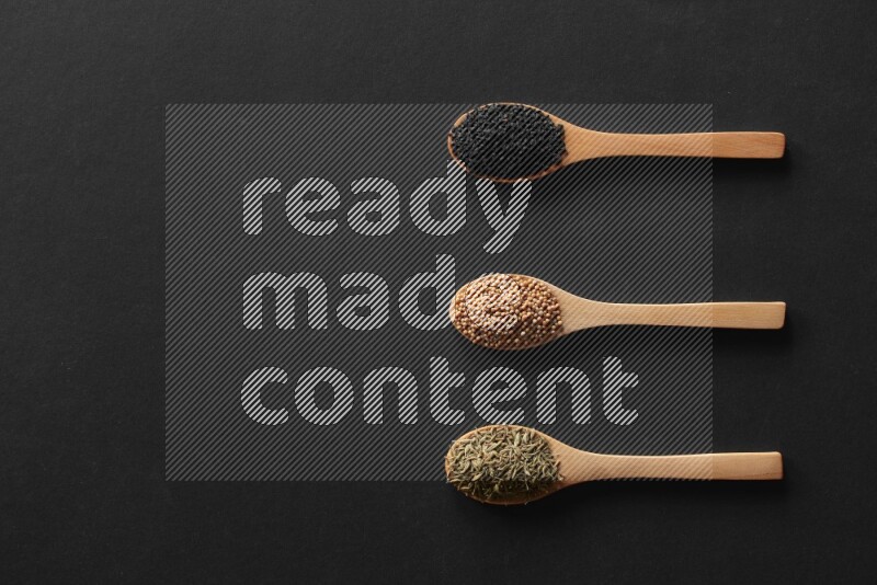 الفلفل الأسود وحبوب الخردل وحبة البركة وحب الرشاد والكمون و حبوب الكتان في معالق خشبية علي خلفية سوداء