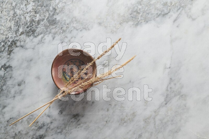 Wheat stalks on decorative pottery plate on grey marble background