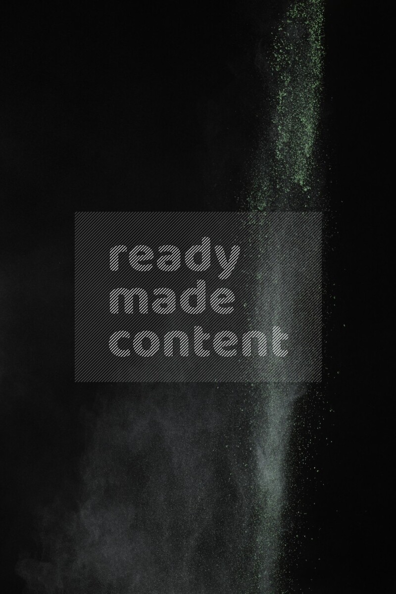 A side view of green powder explosion on black background