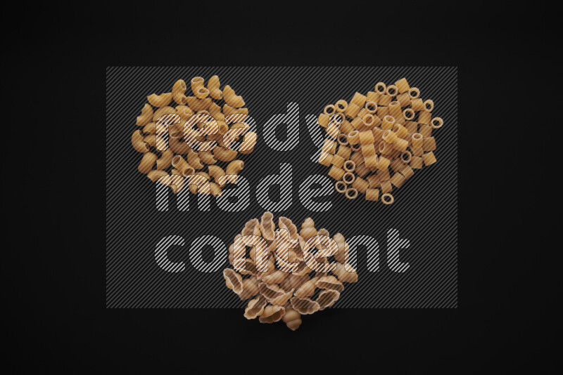 Different pasta types in bunches on black background
