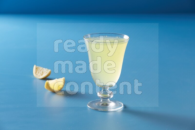 glass of lemon juice on blue background